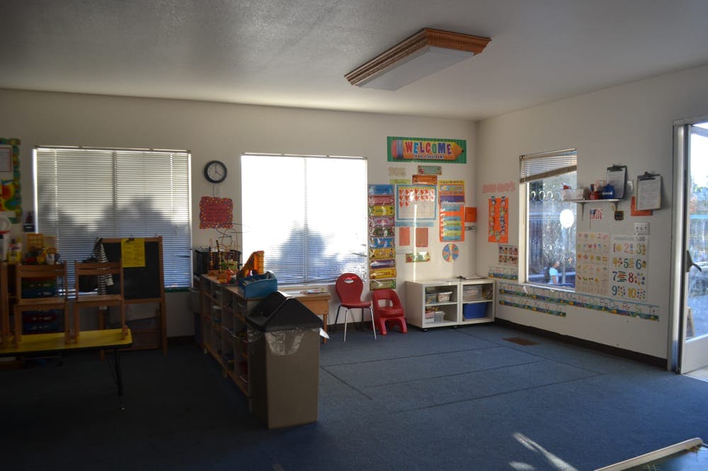 Empty classroom with windows, blue carpet, and educational posters on walls