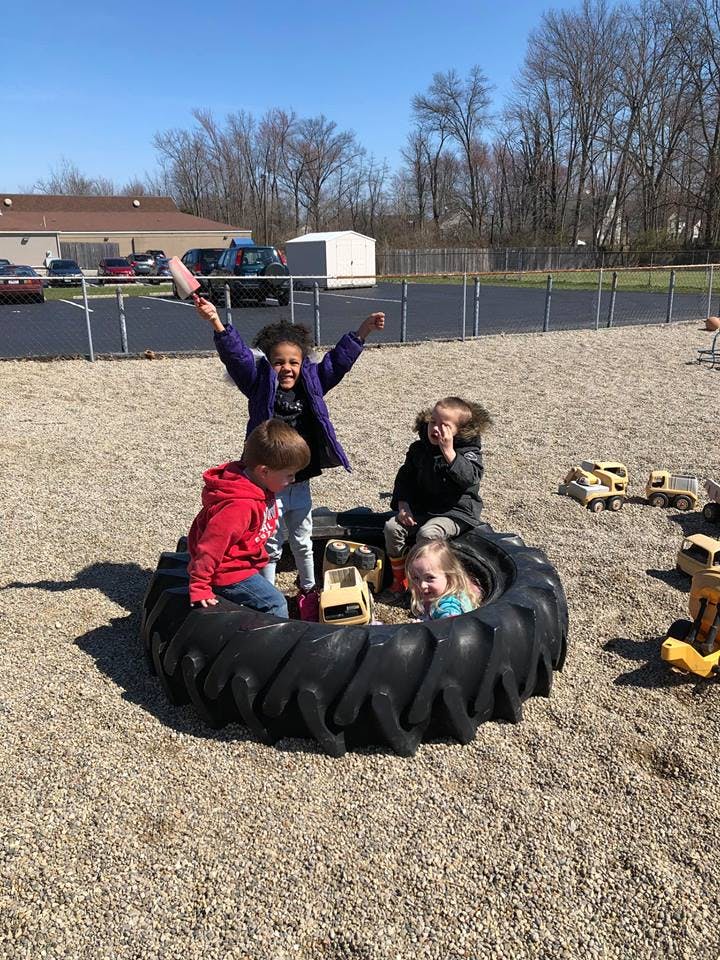 Children playing in a large tire on a gravel playground