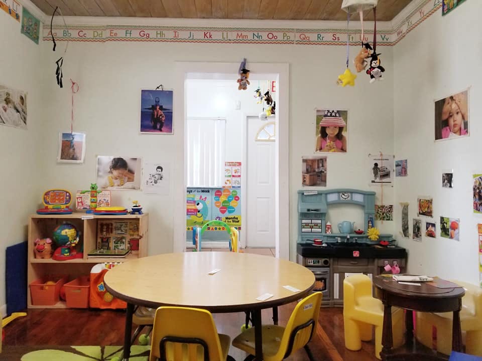 Children's play area with a round table and chairs, shelves with toys, and wall decorations