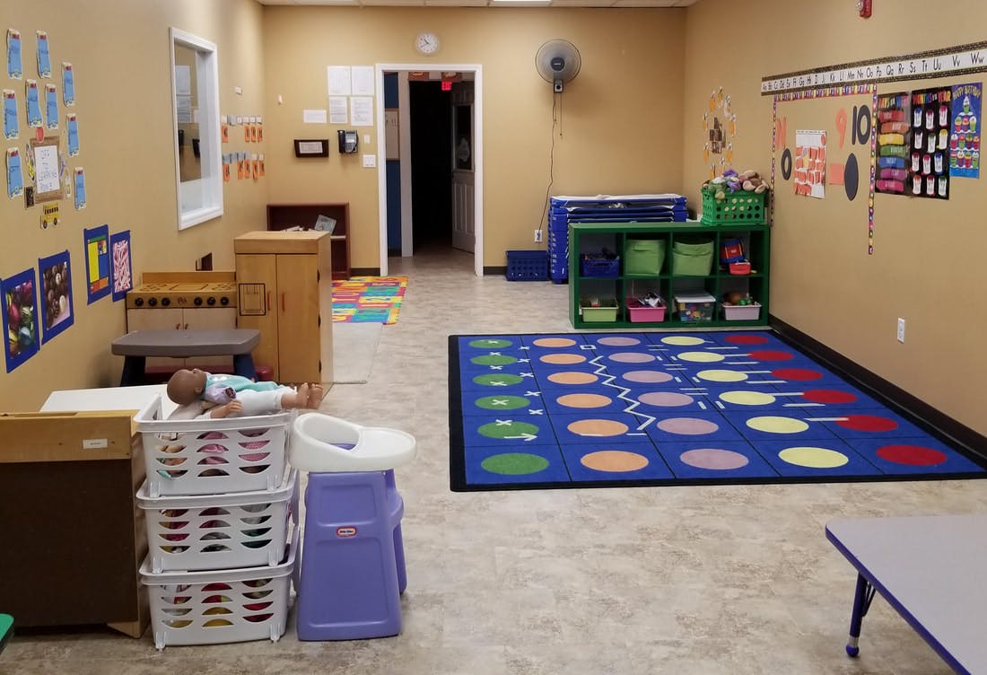 Playroom with a colorful rug, shelves, and a changing table