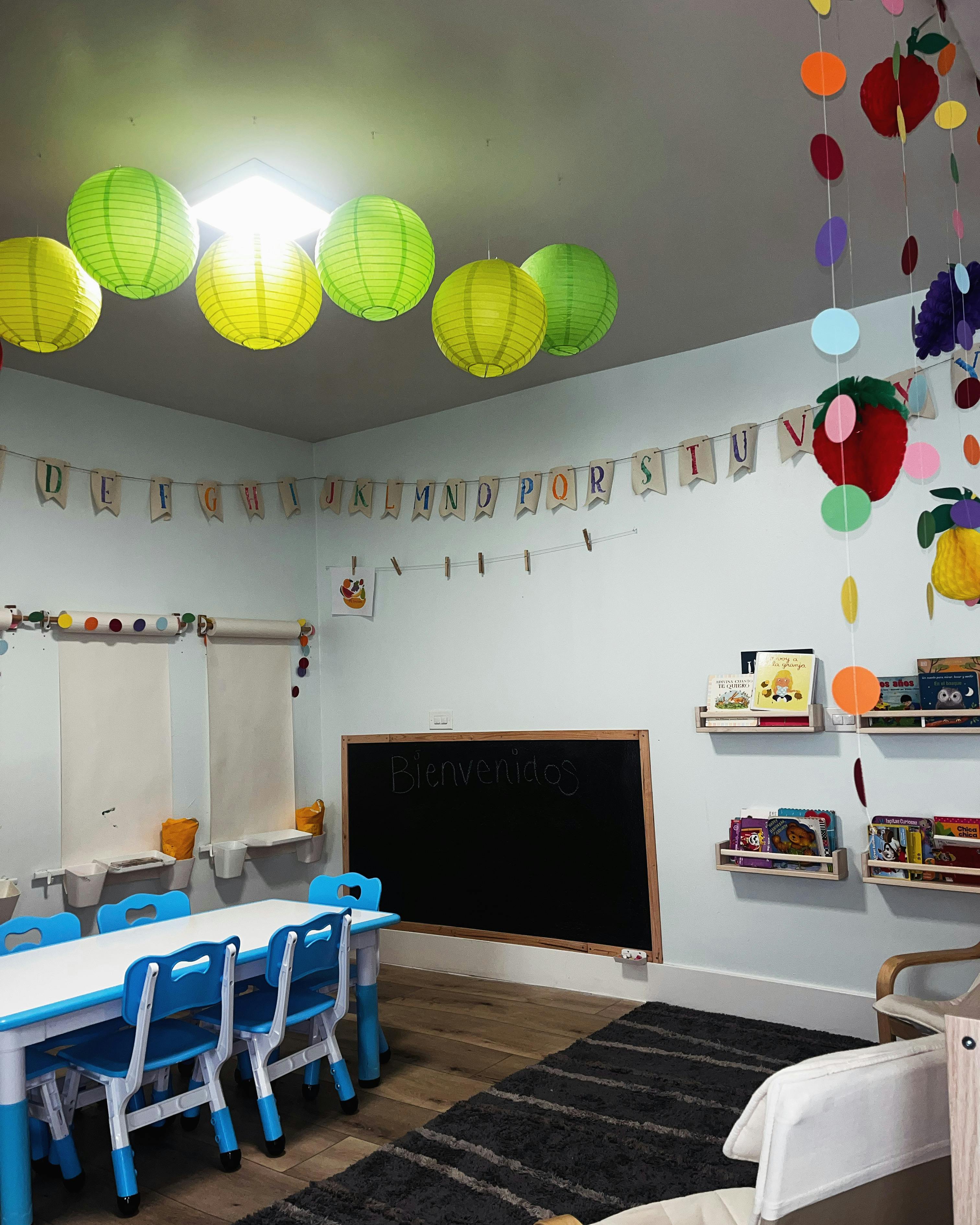 Classroom with small table and chairs, chalkboard, and paper lanterns