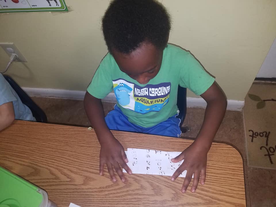 Child looking down at paper on a wooden desk