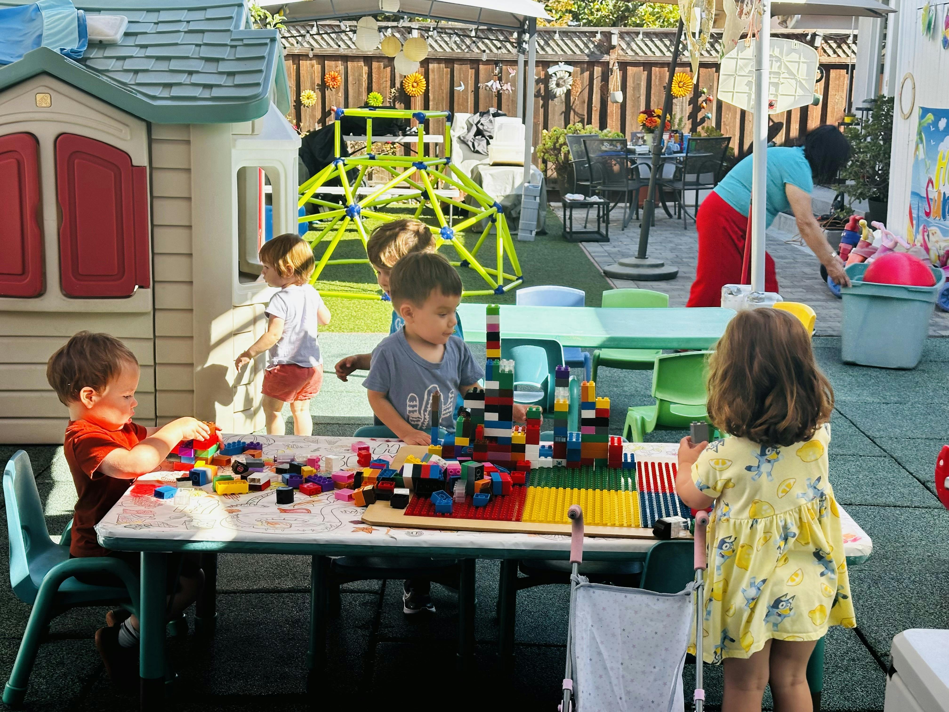 Children playing with colorful building blocks at a table outdoors