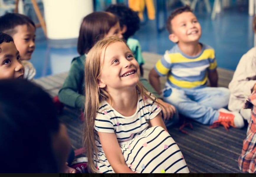 Group of children sitting on the floor looking up