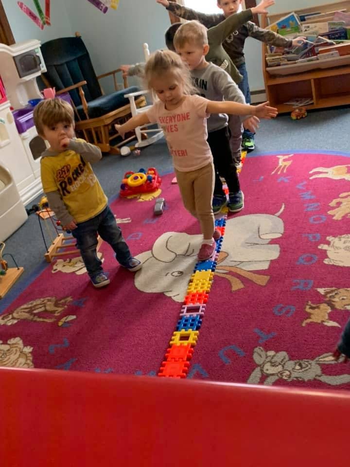 Children balancing on a line of colorful blocks with arms outstretched
