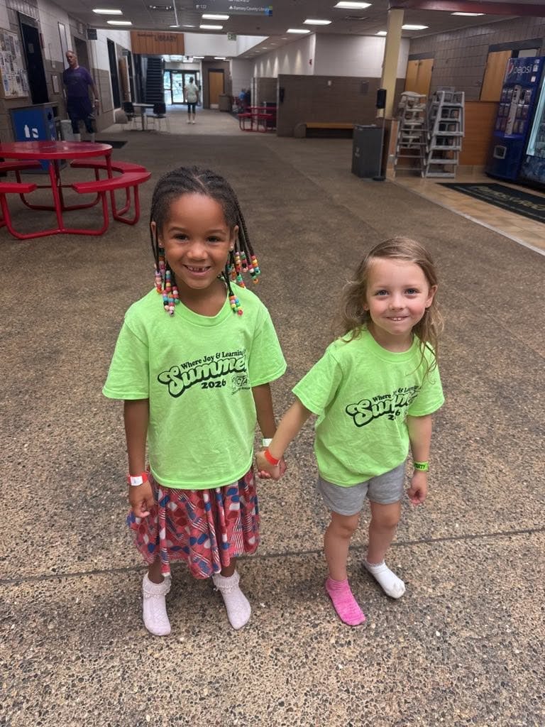 Two children wearing matching lime green shirts holding hands indoors