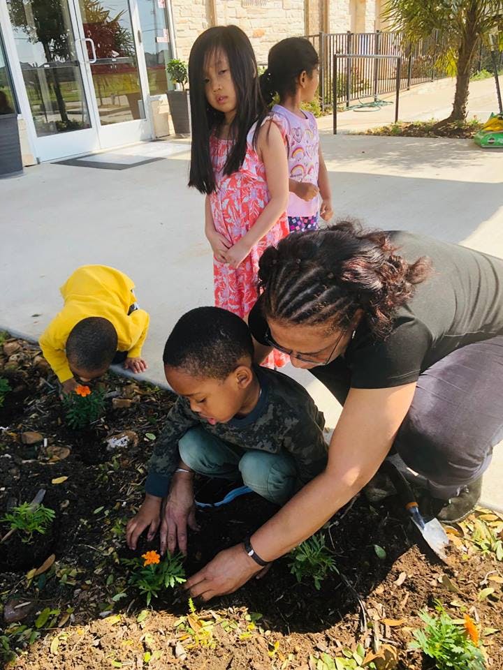 Adult and children planting flowers in a garden