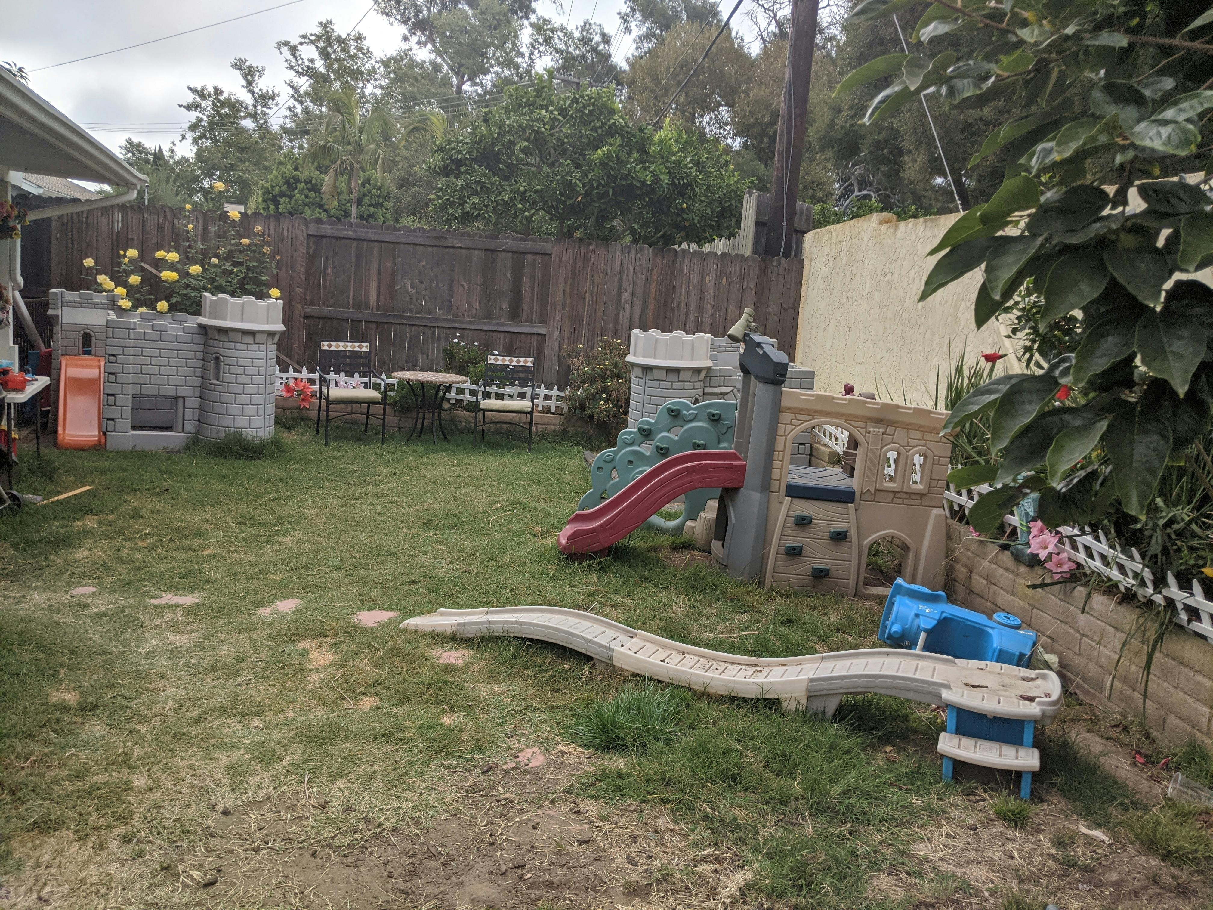 Backyard with play structures, slide, and small tables