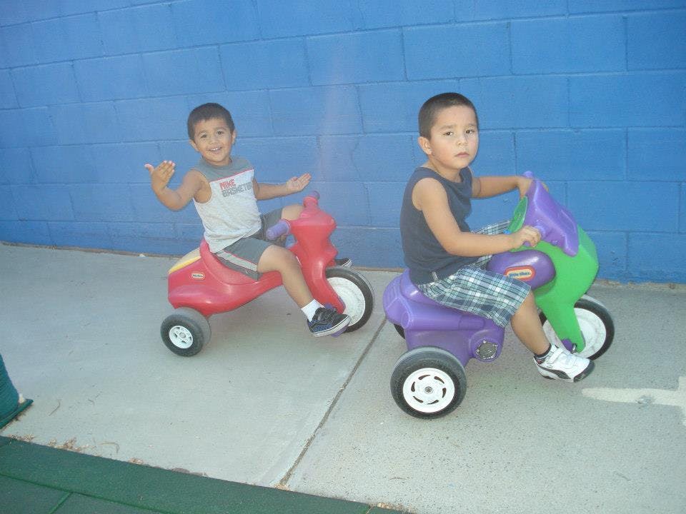 Two children riding toy tricycles