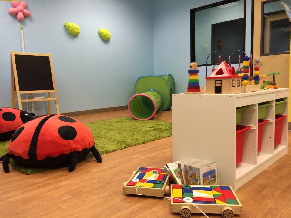 Playroom with a ladybug pillow, green tunnel, and toys on a shelf