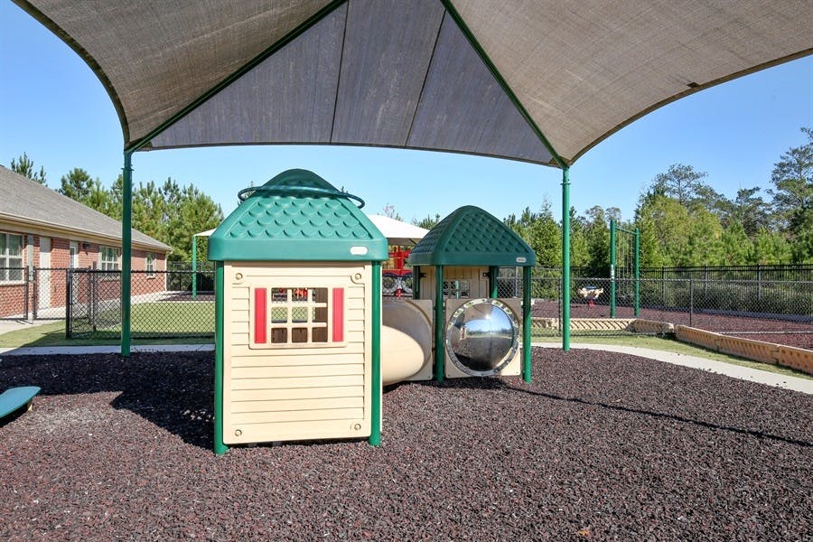 Playground with small playhouse and tunnel under a shade canopy