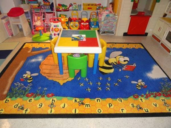 Colorful children's table and chairs on a bee-themed rug in a playroom