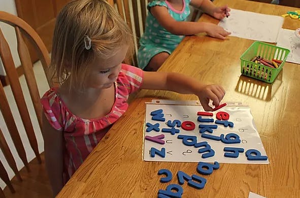 Child playing with magnetic letters on a table