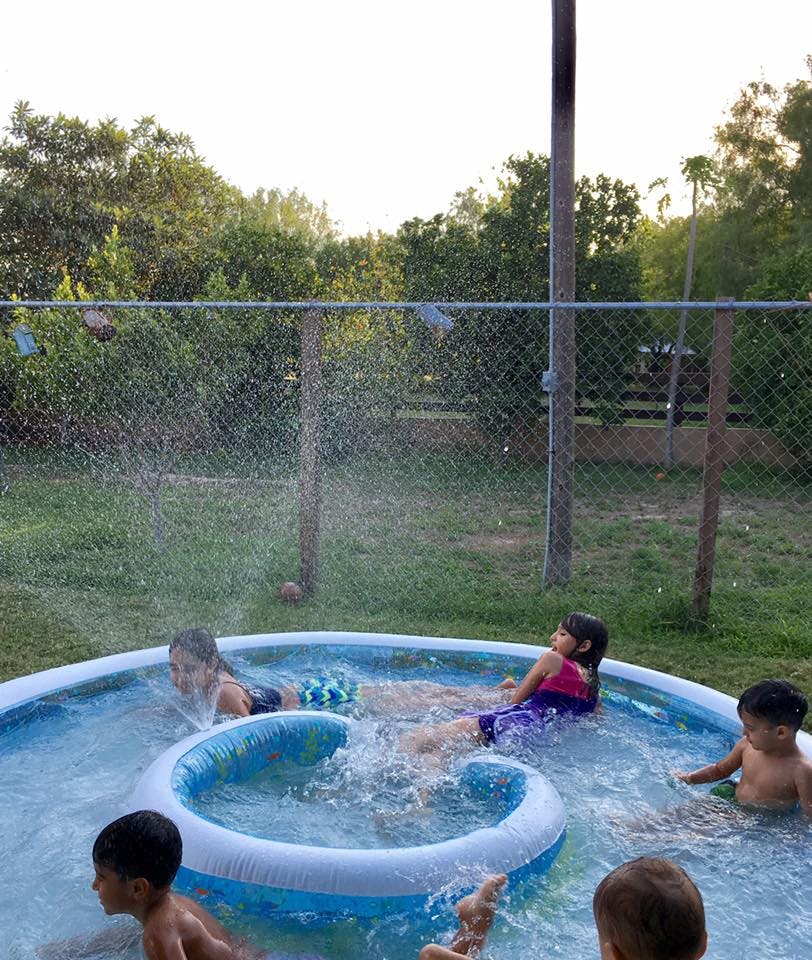 Children playing in an inflatable pool with water spraying