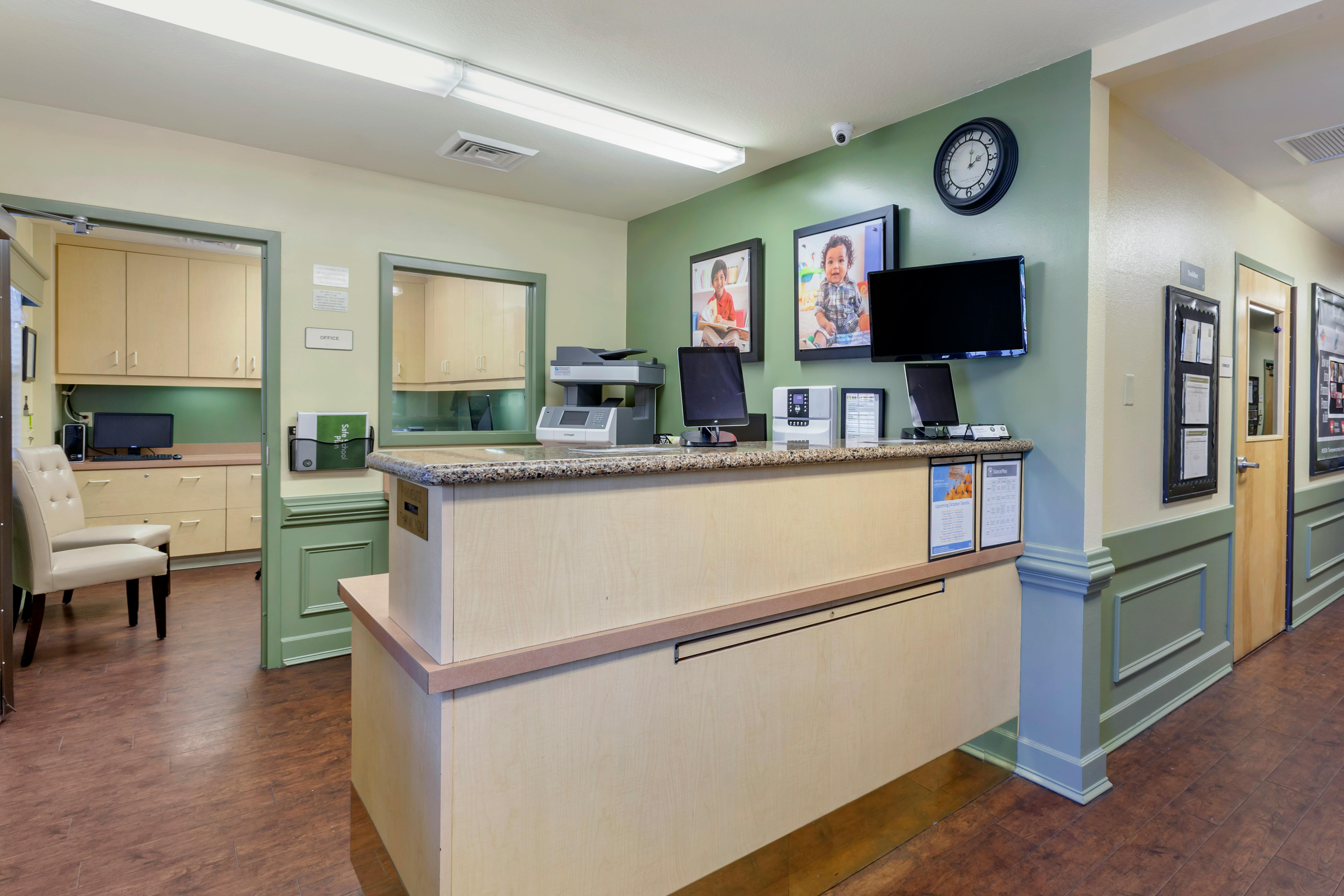 Reception desk with two monitors and two framed pictures on a green wall
