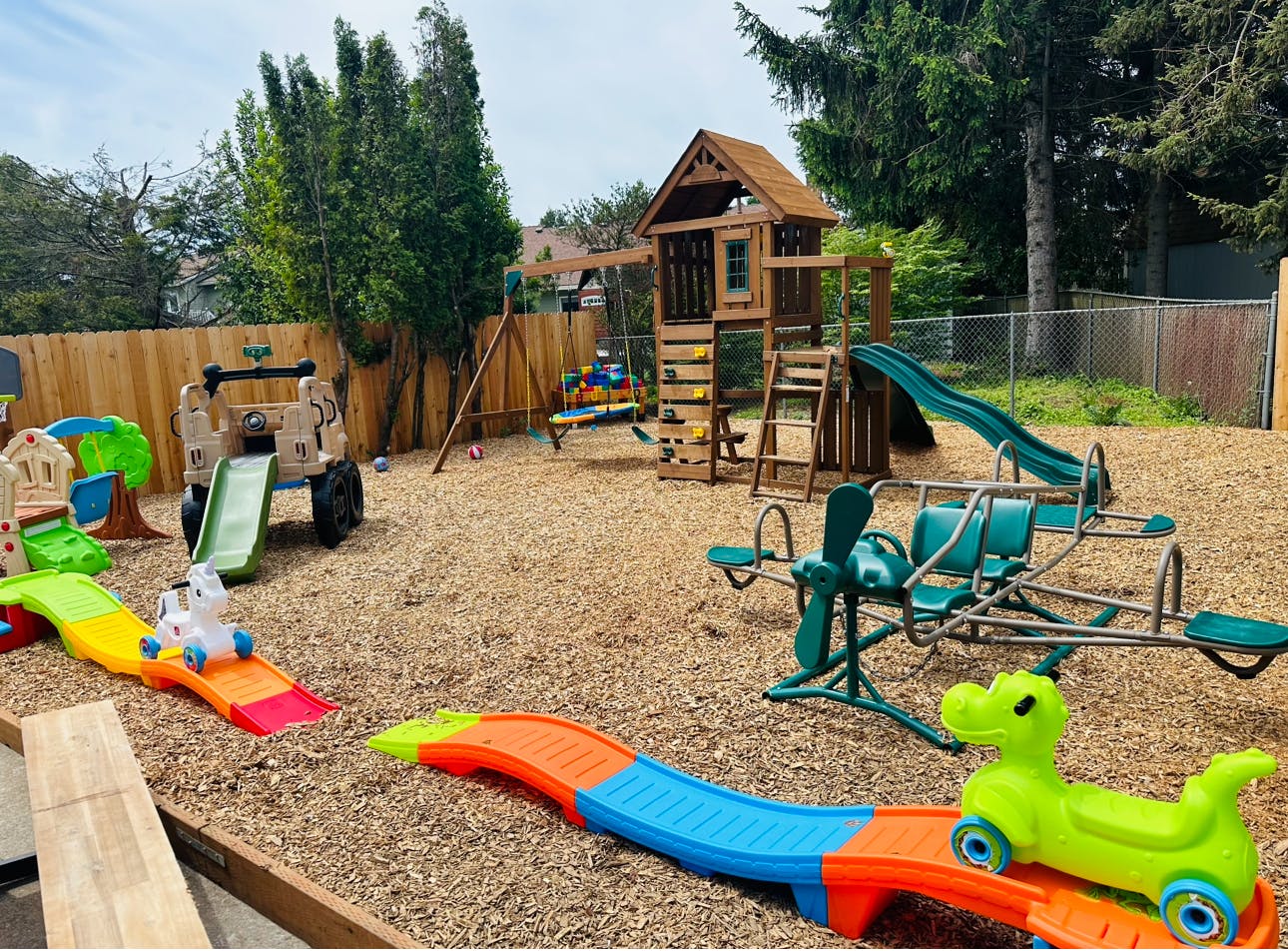 Outdoor playground with various play structures and wood chips on the ground