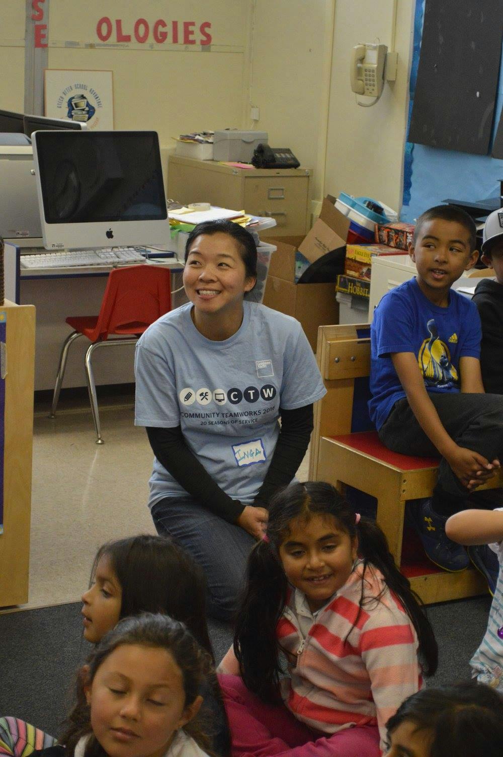 Person kneeling with children in a classroom