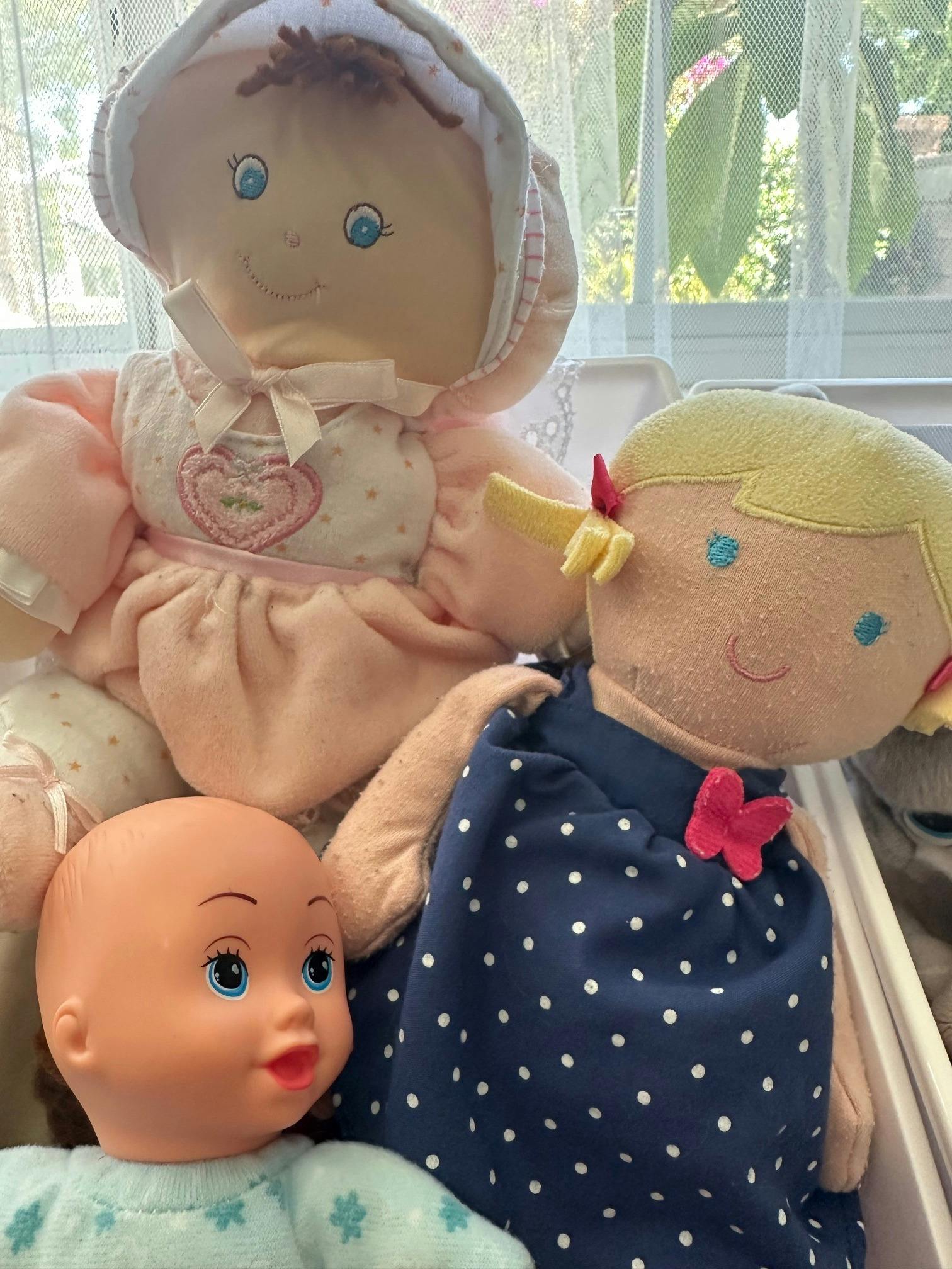 Group of three stuffed dolls in a container