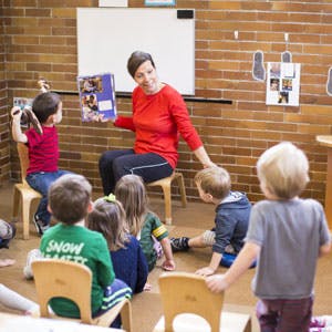 Adult reading a book to children in a classroom
