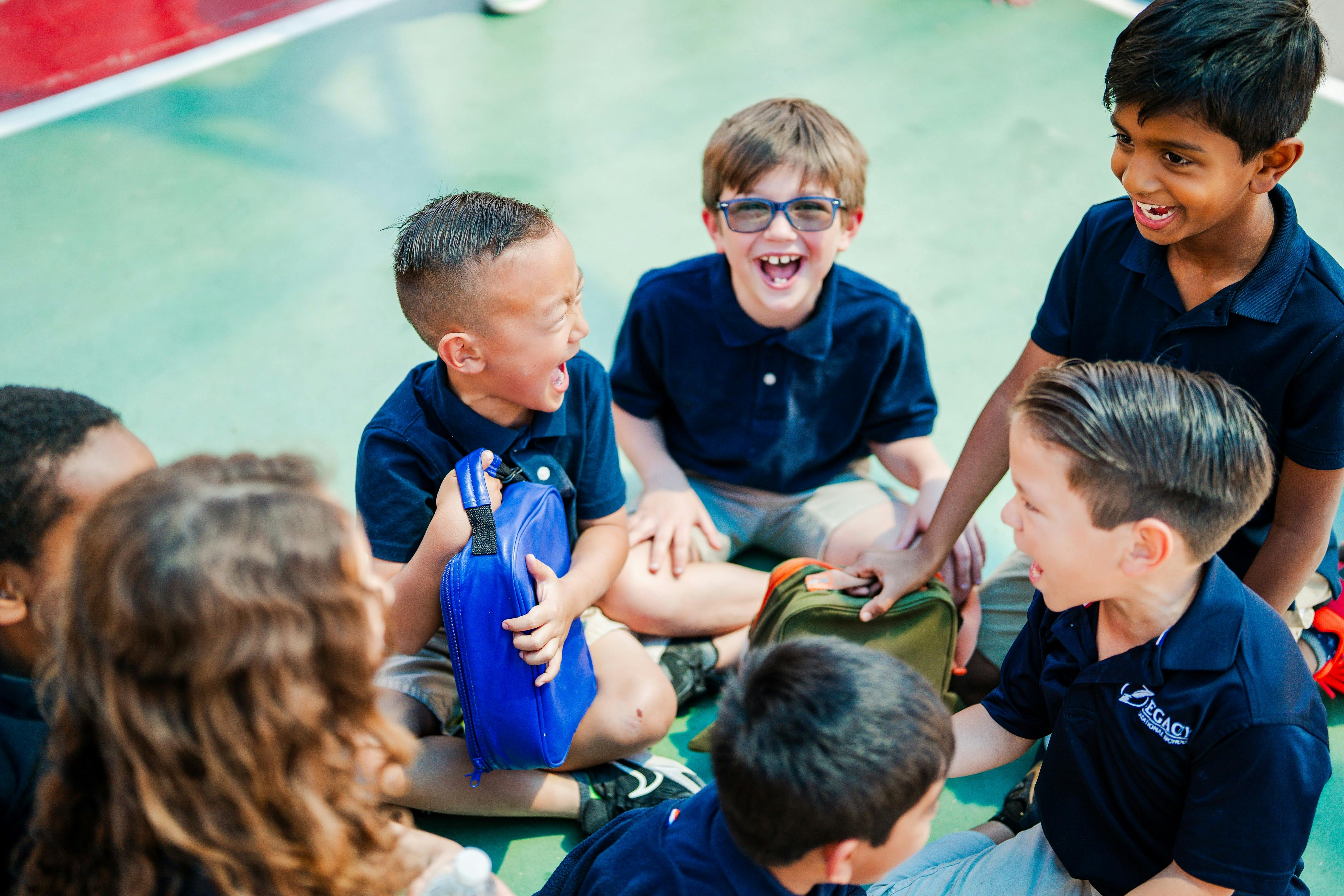 Group of children sitting on the ground, some laughing
