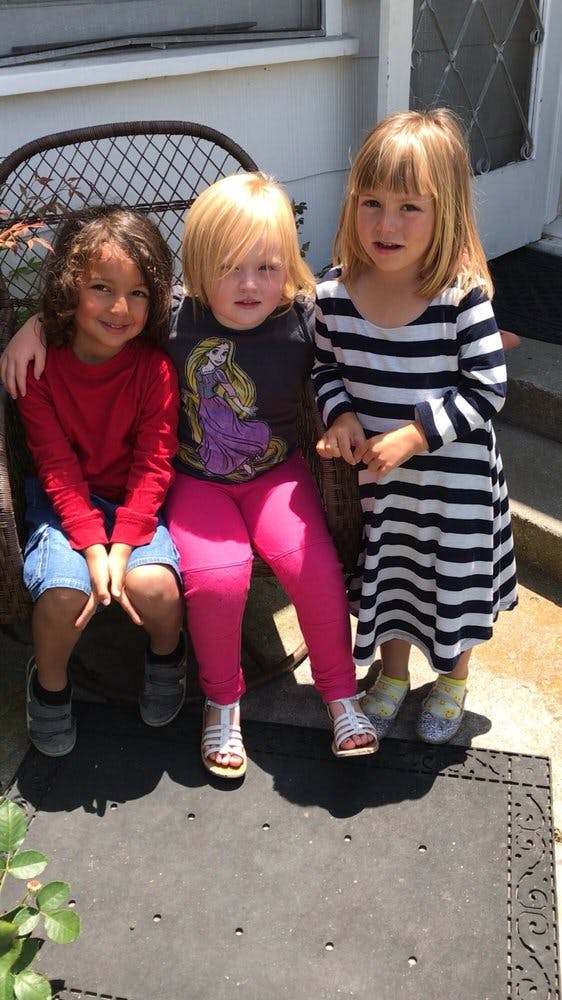 Three children sitting together, one with an arm around another