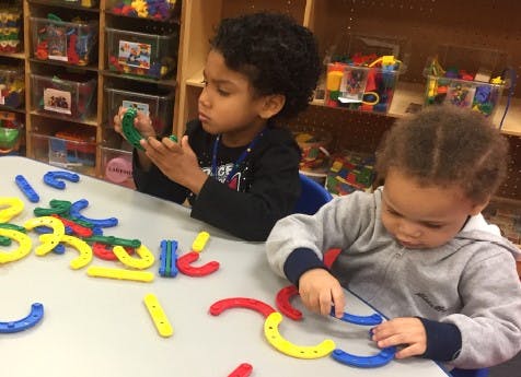 Two children playing with colorful magnetic building toys at a table