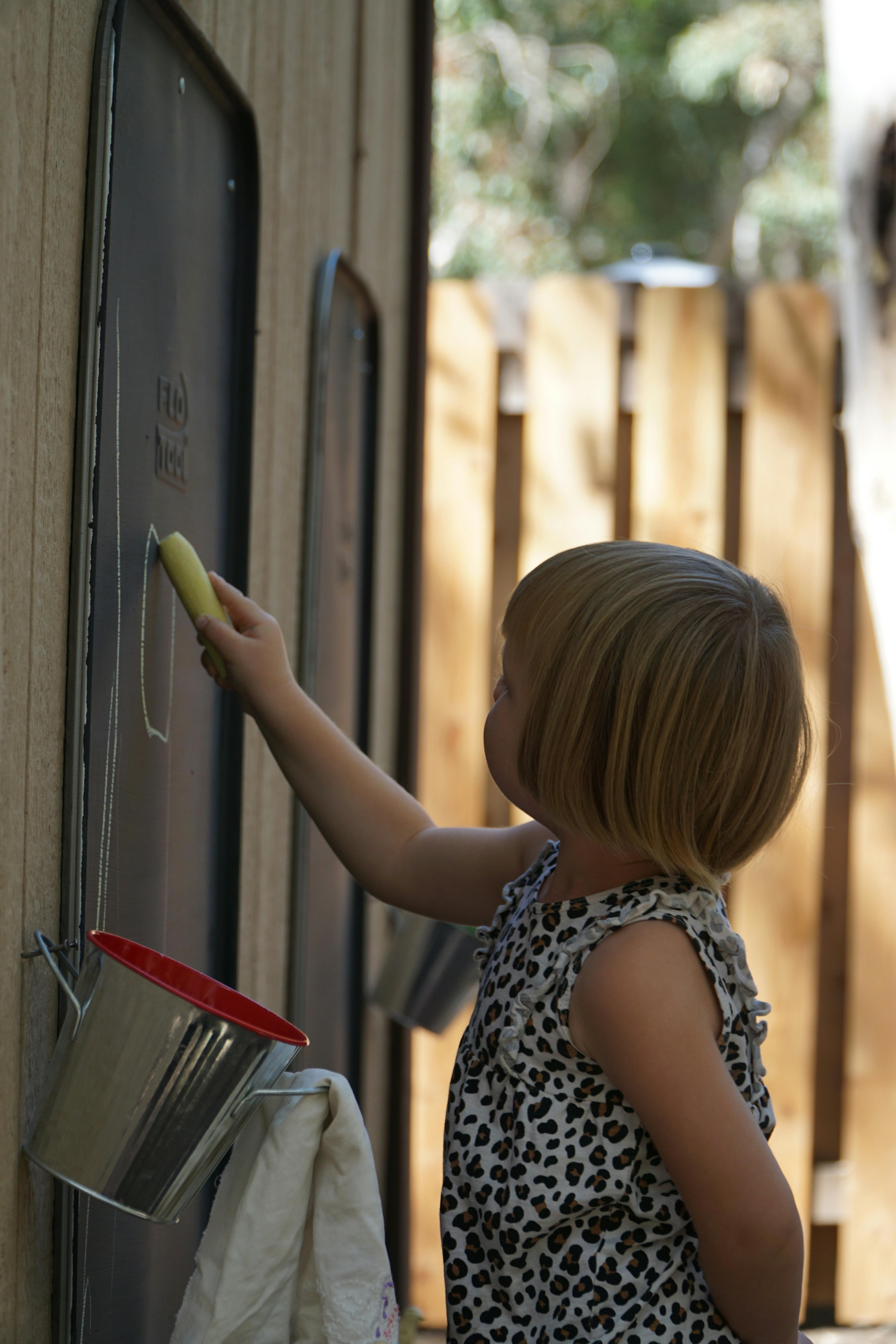 Child drawing on a chalkboard with chalk