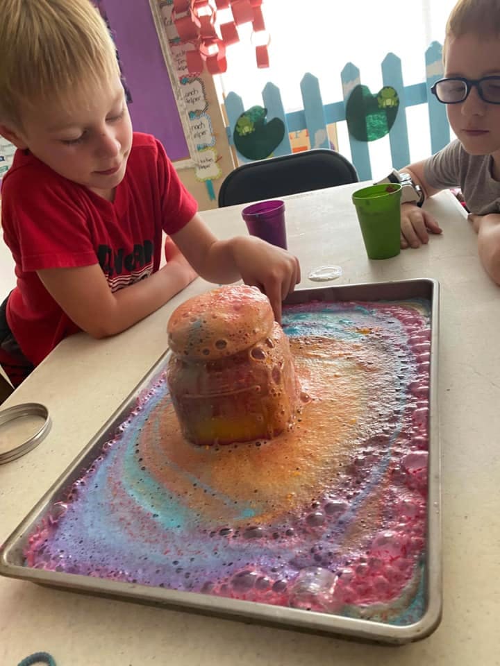 Child watching a science experiment volcano erupting with colorful foam