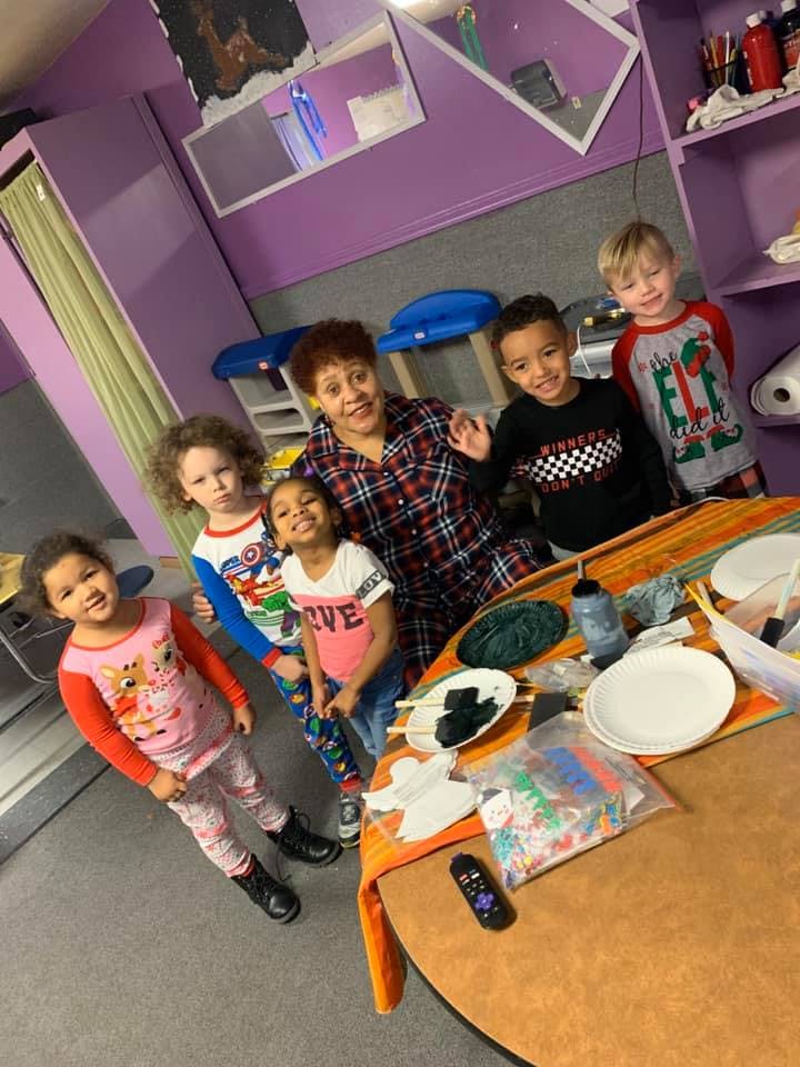 Person and multiple children gathered around a table with craft supplies