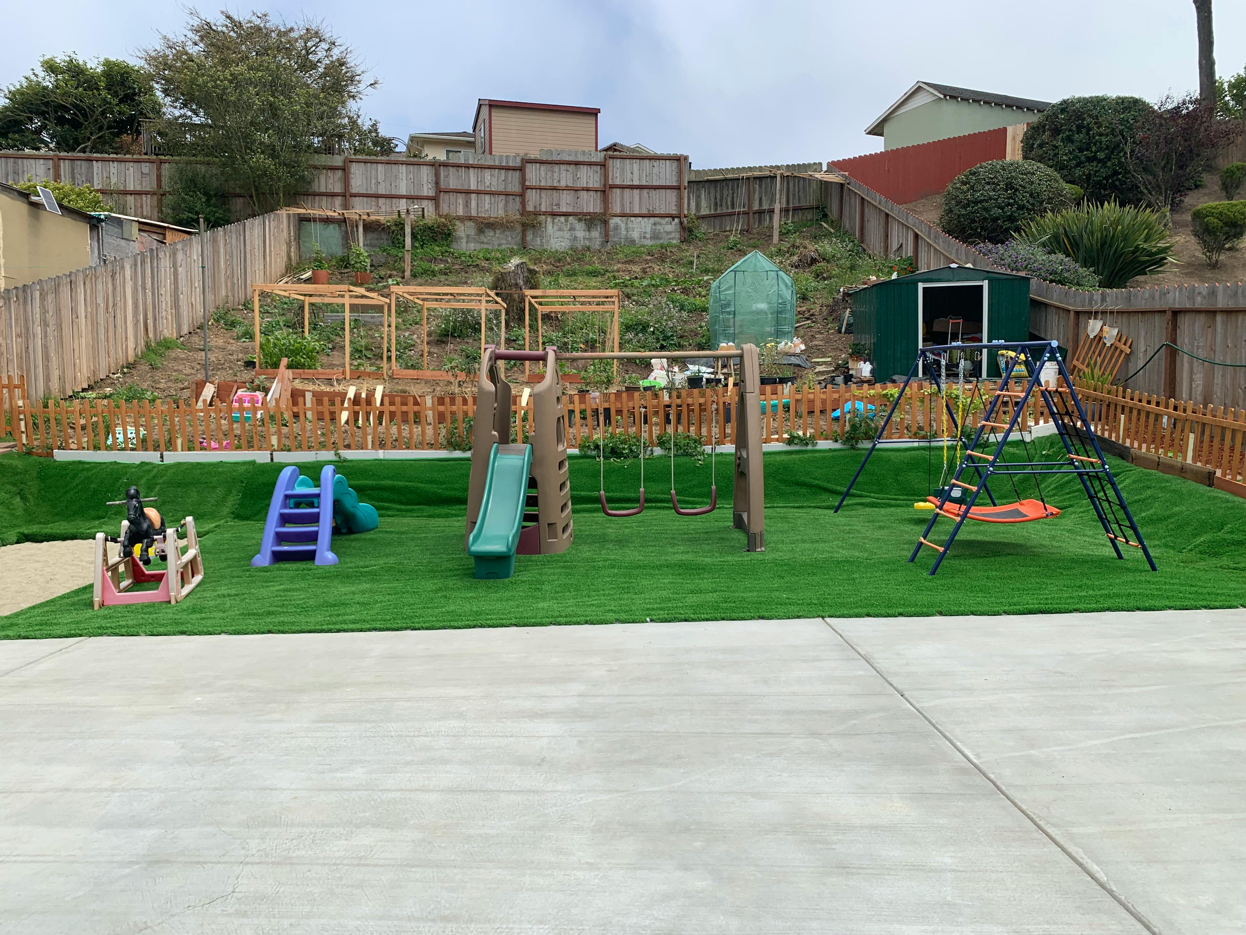Playground with slides, swings, and climbing structures on artificial turf