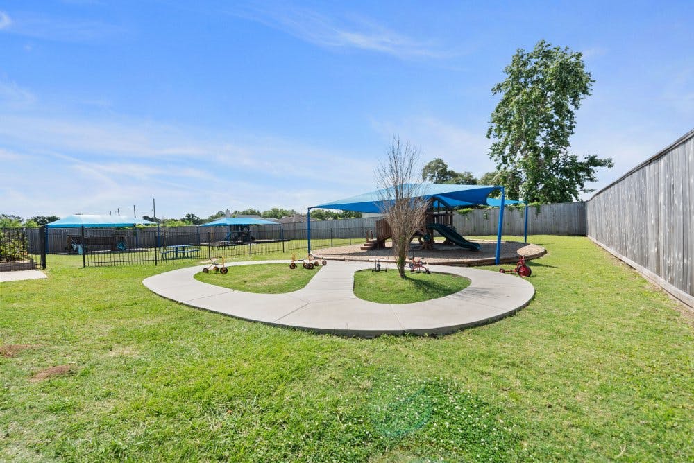 Outdoor playground area with play structures under blue shade canopies