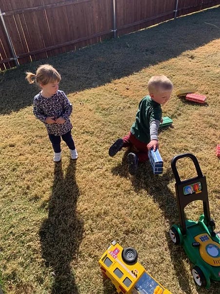 Two children playing with toys on a grassy lawn