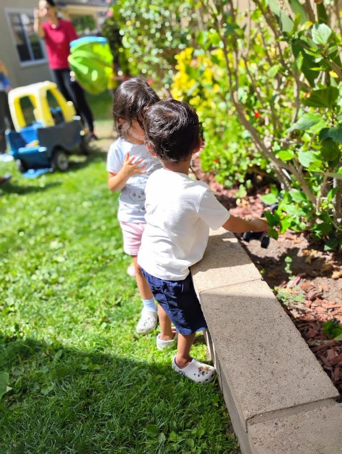 Two children standing by a garden bed
