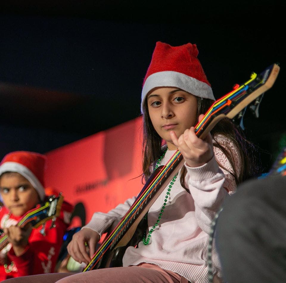 Child in Santa hat playing a guitar