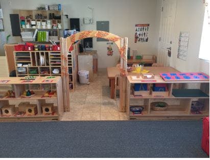 Classroom with wooden shelves, tables, and an arched doorway