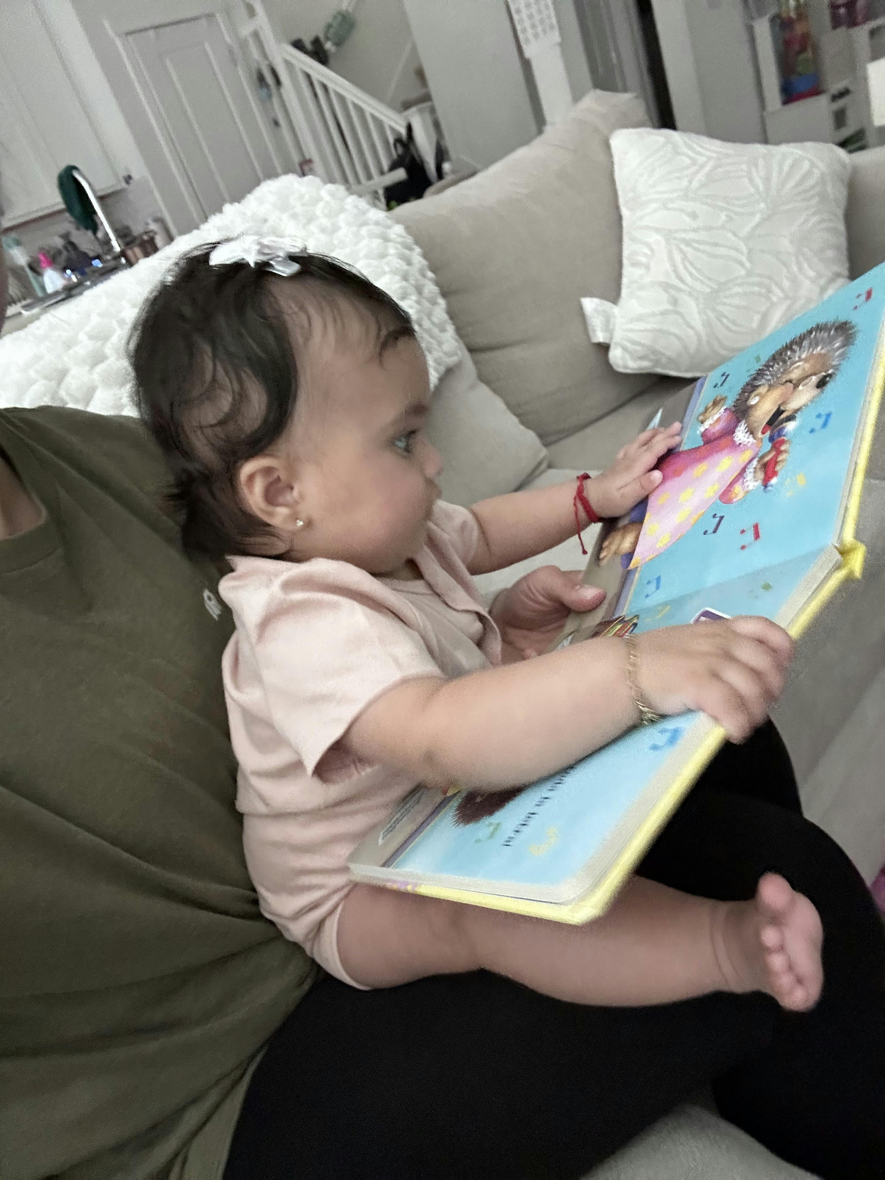 Child sitting on a person's lap, looking at an open book