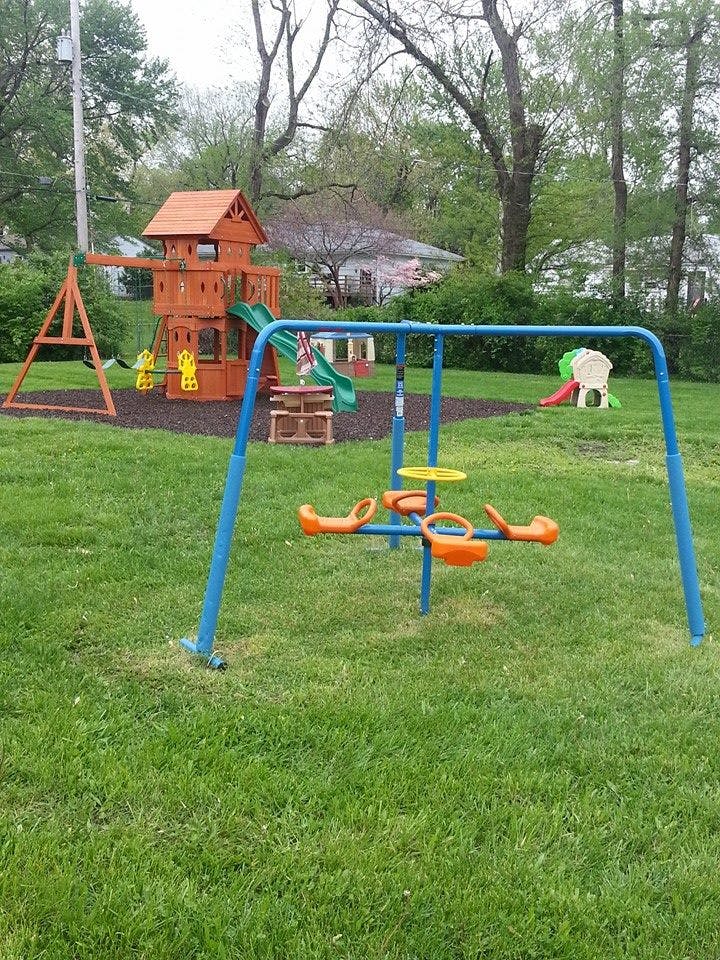 Playground with a wooden playset, swings, and a blue merry-go-round