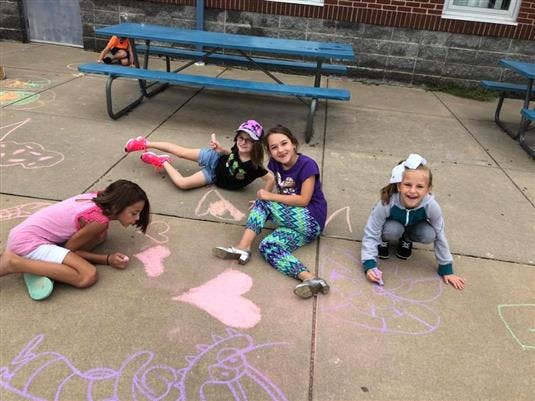 Four children drawing with chalk on pavement