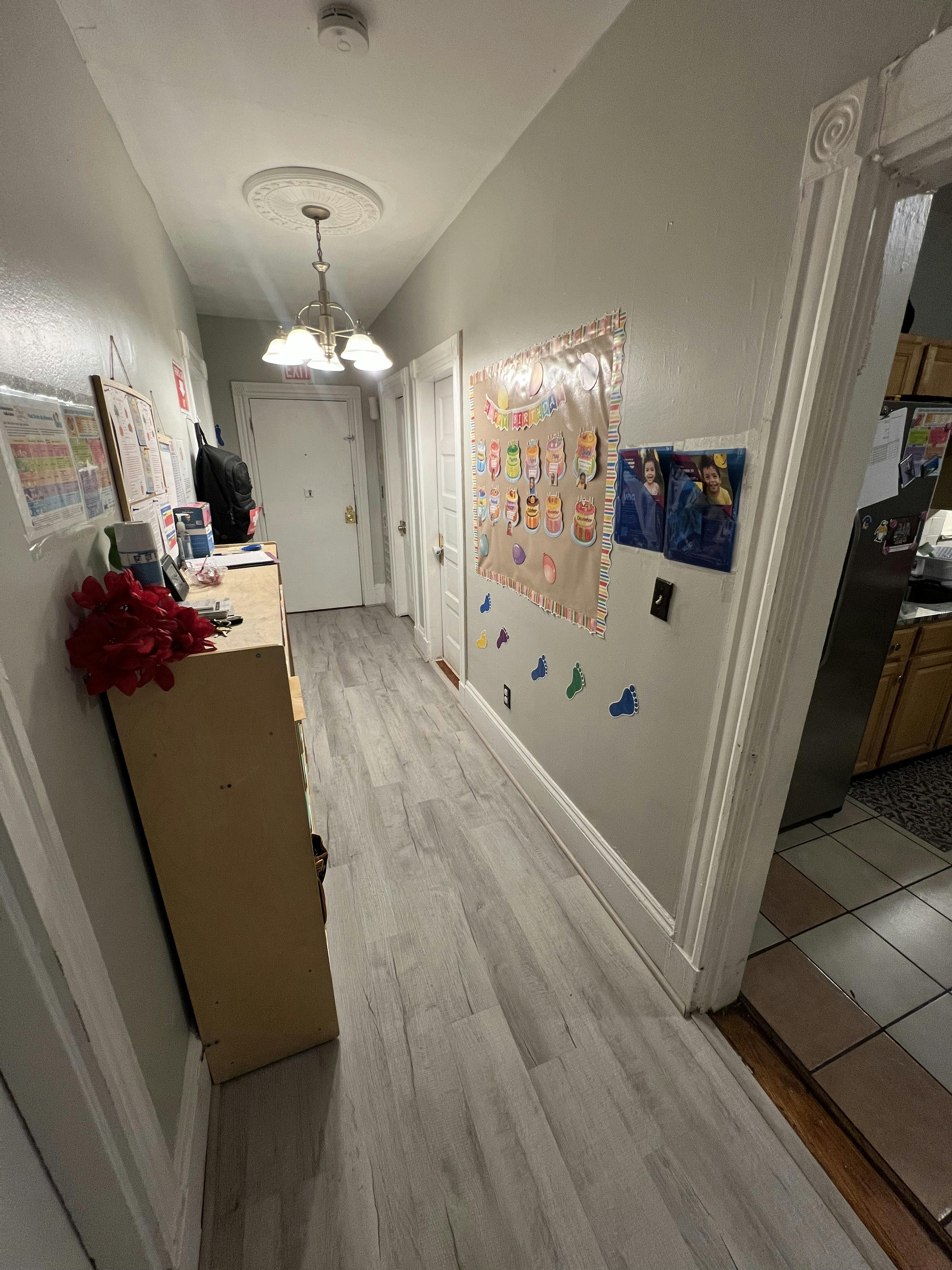 Hallway with light wood flooring and a dresser with red flowers