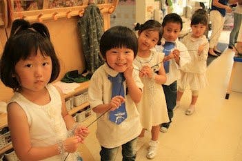 Five children in a line holding a string