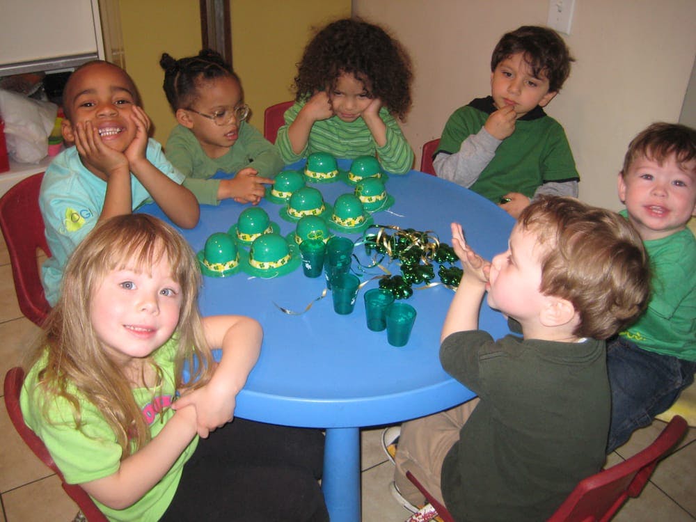 Children sitting around a table with green cups and decorations