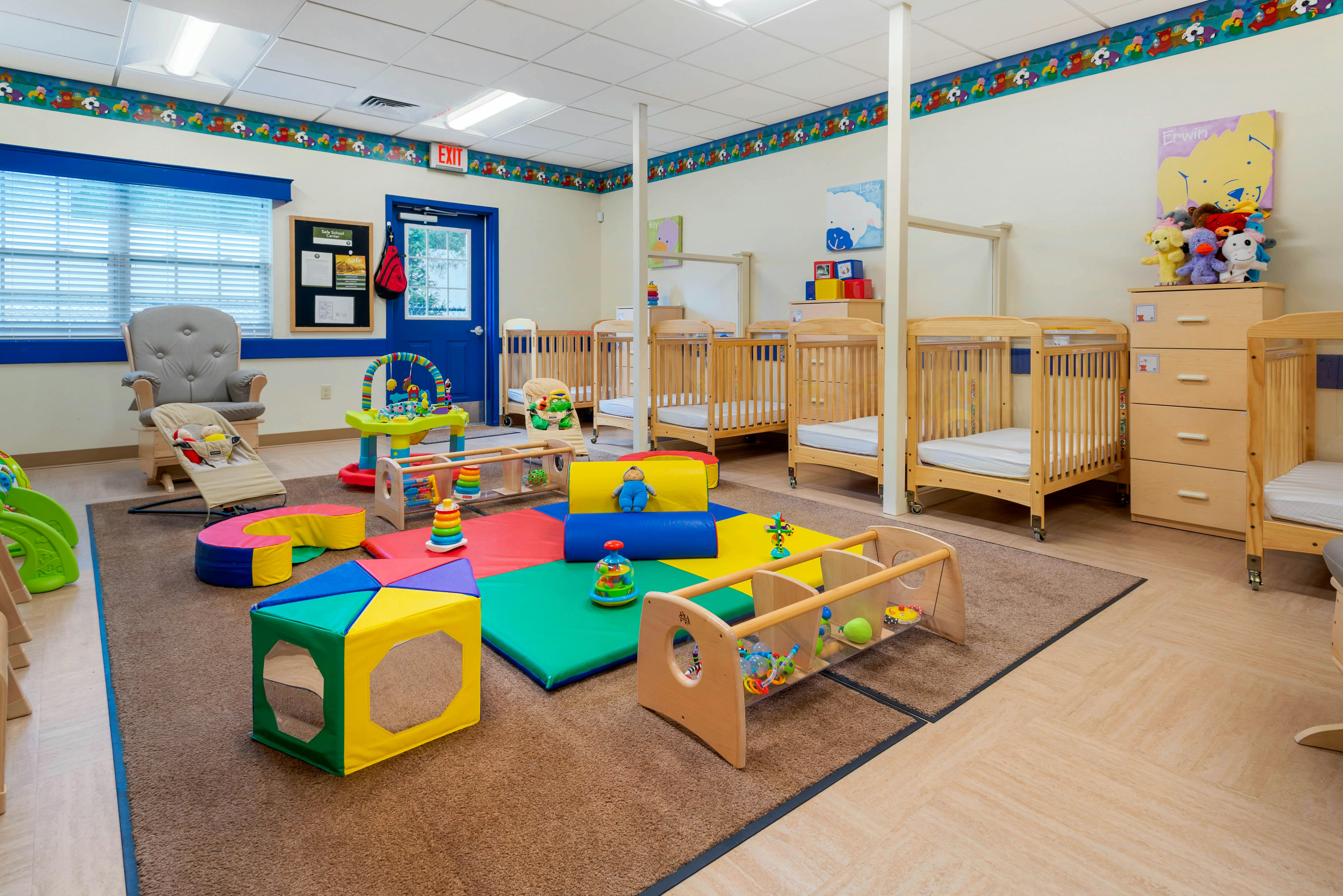 Cribs and play area in a brightly lit nursery room with soft play mats