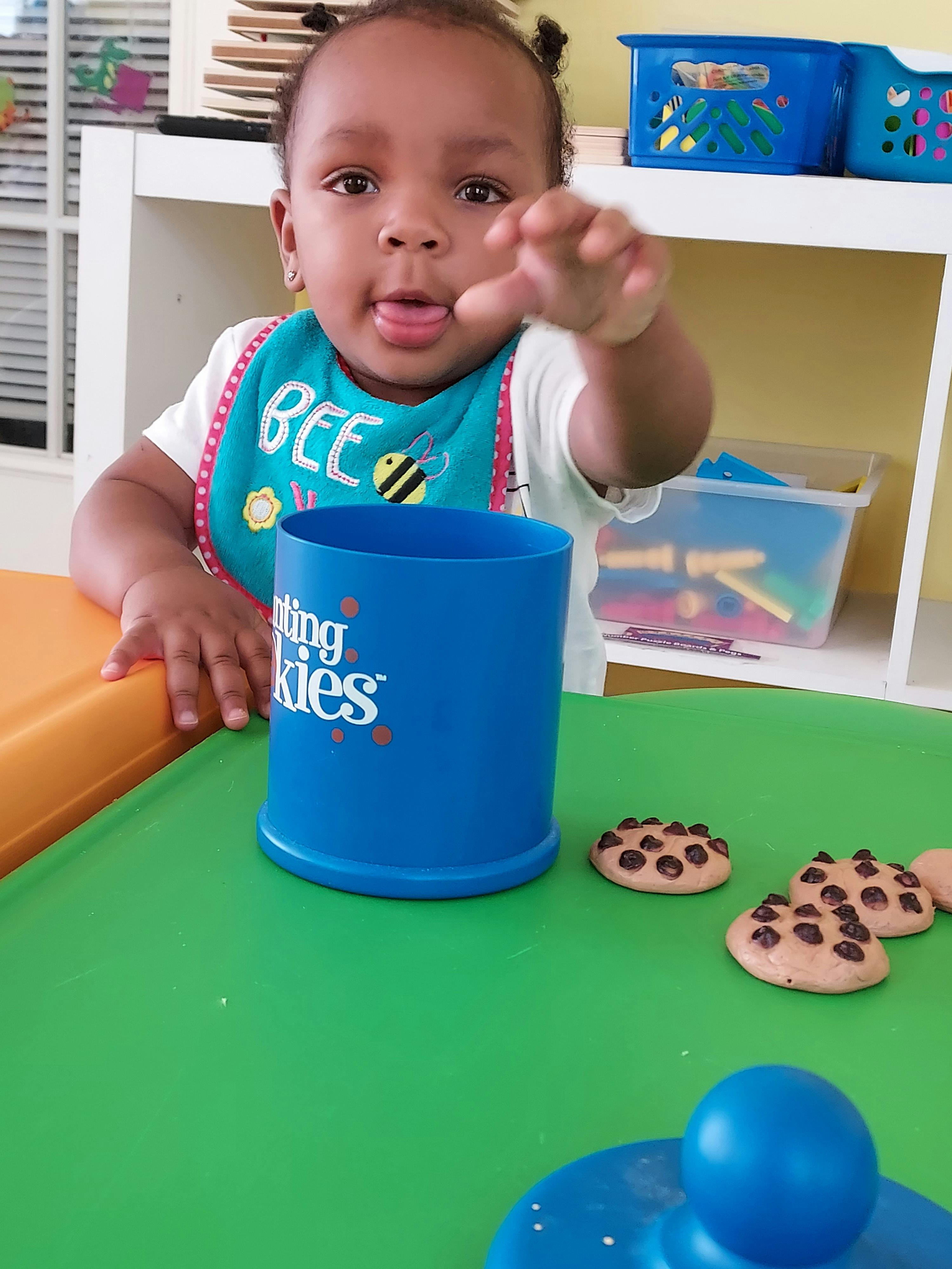 Child reaching for cookies on a green table