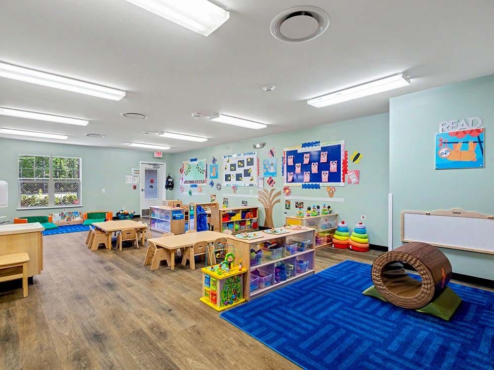 Empty colorful children's classroom with small tables, chairs, and toys