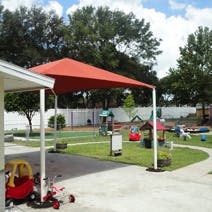 Red shade structure over a paved area next to a playground