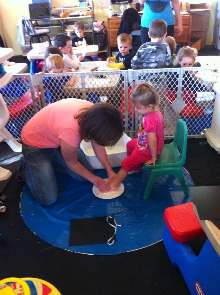 Person washing a child's foot in a classroom