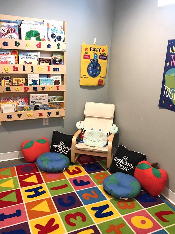 Children's reading nook with a bookshelf, chair, and alphabet rug