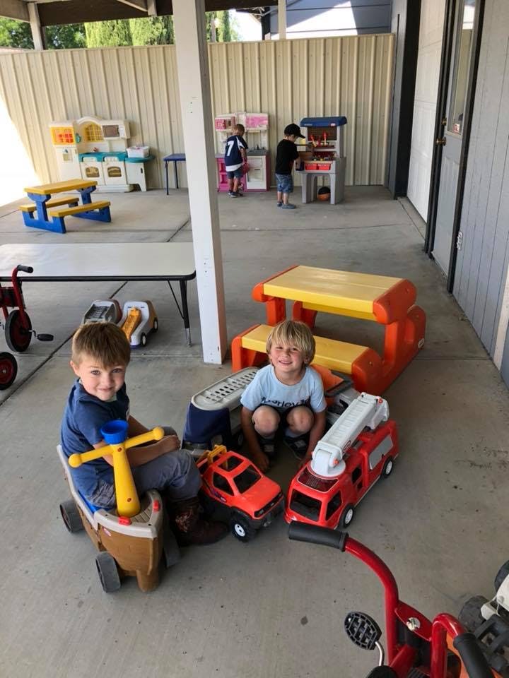Two children playing with toy vehicles on a patio