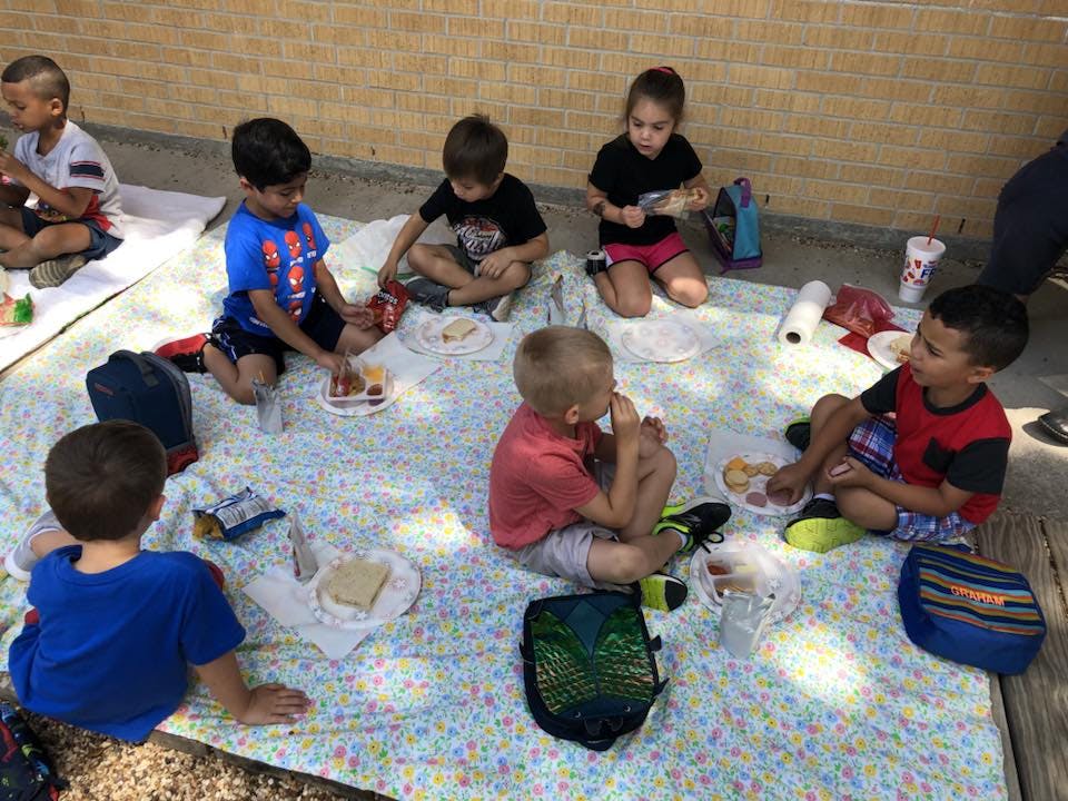 Children sitting on a blanket eating snacks