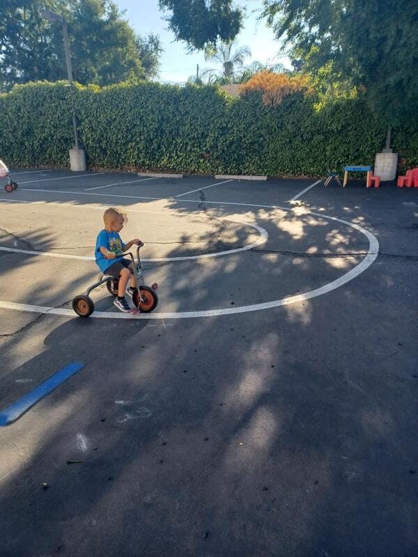 Child riding a tricycle on an asphalt surface